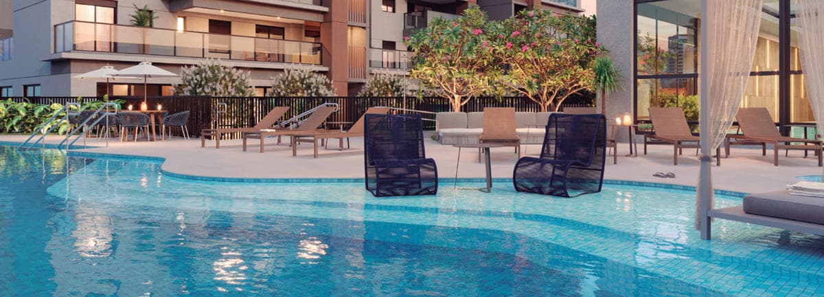 Piscina externa vista rente à água, com cadeiras submersas, espreguiçadeiras e a torre ao fundo